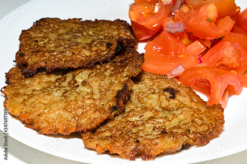 Polish potato pancakes with chopped tomato salad. Placki Ziemniaczane Recipe