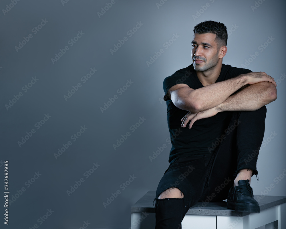 A portrait of a handsome man wearing black t shirt while sitting on a chair front of a table A portrait of a handsome man wearing black t shirt while sitting on a chair front of a table