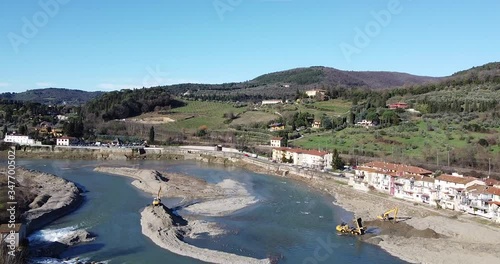 Water escavators working inside Arno river near Sieci town, Pontassieve, to avoid another Florence disaster flood afer latest November rainy long season. Sunny day Winter, Tuscany. Italy photo