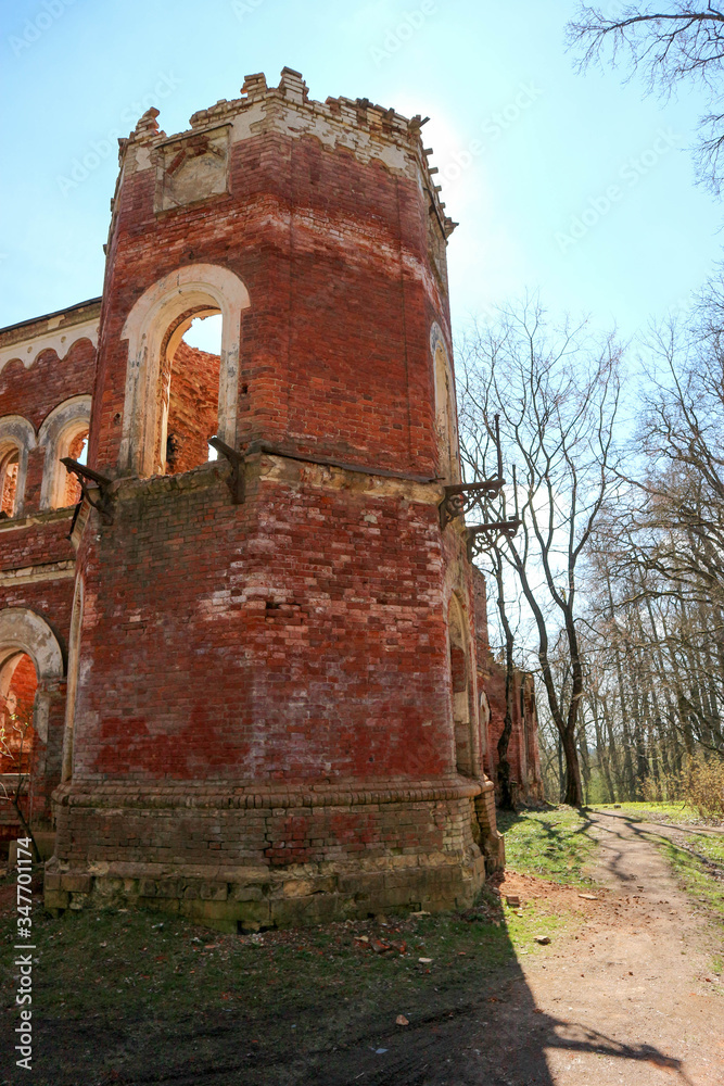Naklejka premium old red brick tower in the abandoned ruined castle estate of baron Vrangel in Russia at sunny spring day