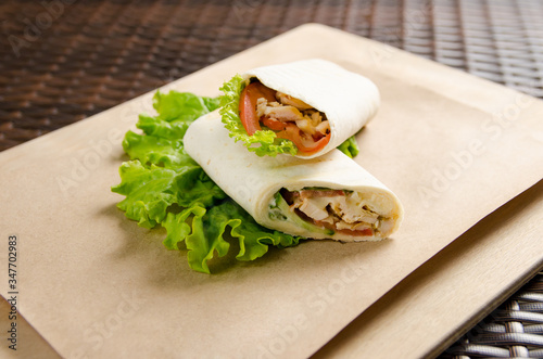 chicken roll with a onion, lettuce on a paper sheet