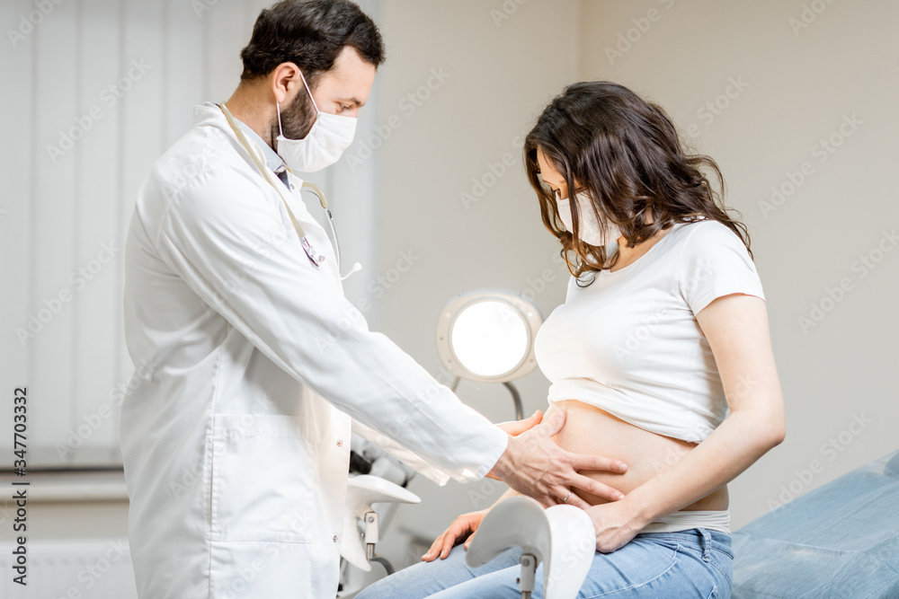 Doctor with a pregnant woman in medical masks during an examinations. Concept of new rules for the use of masks in medicine after or during a pandemic Doctor with a pregnant woman in medical masks during an examinations. Concept of new rules for the use of masks in medicine after or during a pandemic