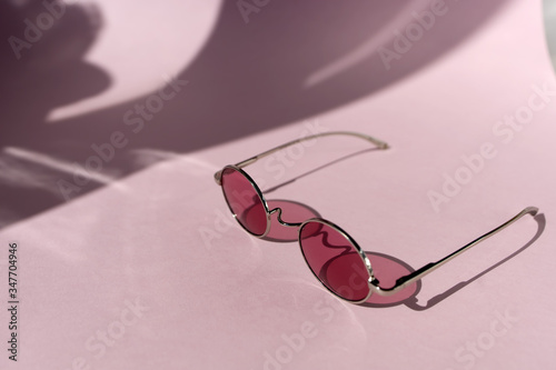 Pink sunglasses on the light pink background. Summer concept. Different shadows. Copy space.Place for text and design.