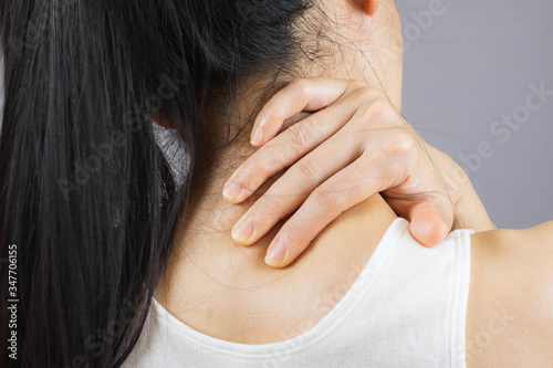 selective focus woman with neck pain.Acute pain in a female nape holding hand to spot of Behind the scruff.health care concept
