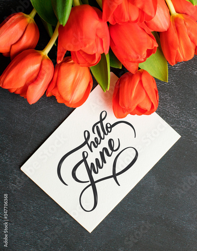 Hello June hand lettering card. Bright red flowers on black background.