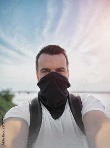 selfie of man with black buff on face as mask. tourist travel with face protection.