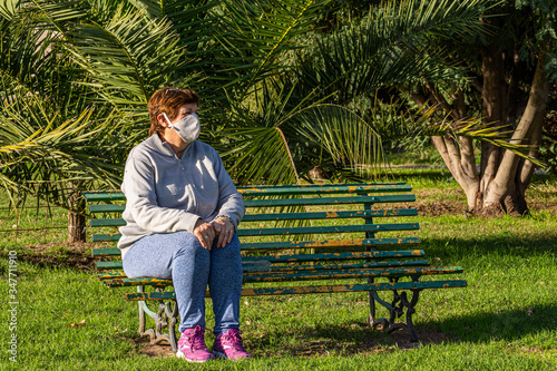 Abuela sentada en parque cuidándose del covid-19 photo