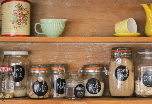Antique Wooden Kitchen Hutch with retro crockery and an assortment of glass jars containing baking ingredients and staples like flour, sugar and pasta. 