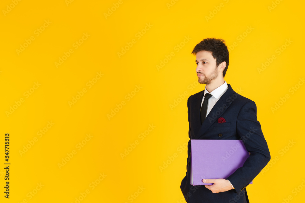A young businessman in a suit is holding a document file and reach out a hand to hold the hand on the yellow isolated background. Business image for banners.