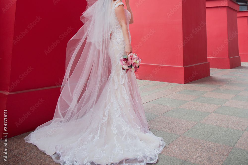 Obraz premium long veil of a bride against a red wall