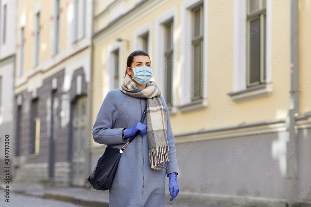 Fototapeta premium health, safety and pandemic concept - young woman wearing protective medical mask on empty street of old town in tallinn city