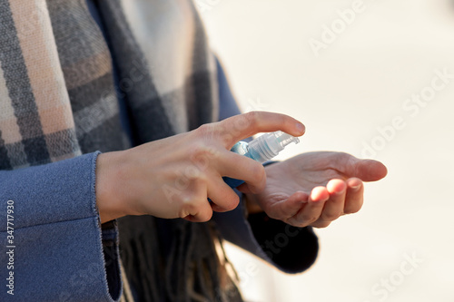 hygiene, health care and safety concept - close up of woman applying antibacterial hand sanitizer outdoors