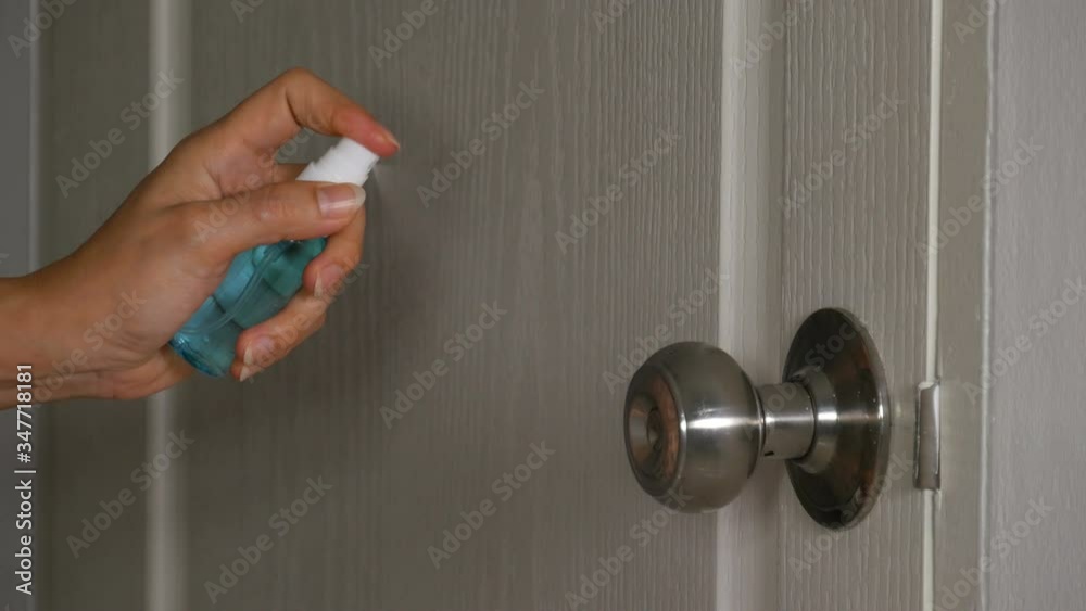 hand spraying alcohol to cleaning door knob for protect from infection