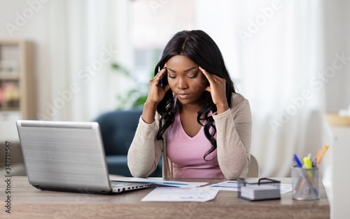 remote job, technology and people concept - stressed young african american woman with laptop computer and papers working at home office