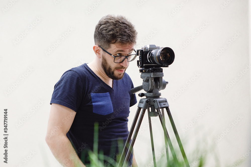 Bearded videographer in glasses with a camera.