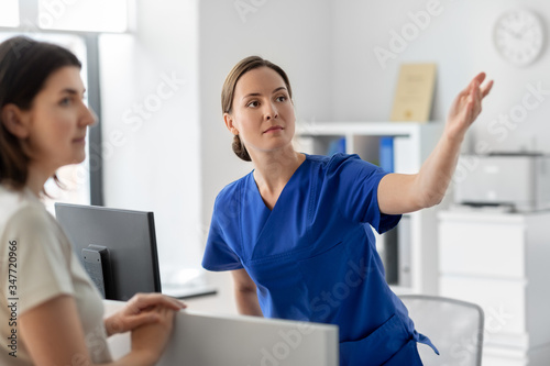 medicine  people and healthcare concept - female doctor or nurse showing something to patient at hospital