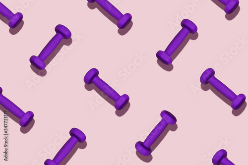 Do sport at home. Group of purple dumbbells on a pink background. © Aleksandra Abramova