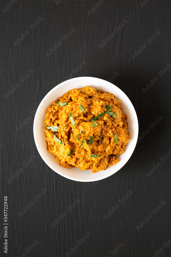 Homemade Chicken Tikka Masala in a white bowl on a black surface, top view. Flat lay, overhead, from above. Homemade Chicken Tikka Masala in a white bowl on a black surface, top view. Flat lay, overhead, from above.