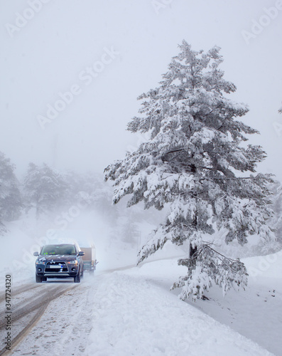 Car (SUV) moving on snowy road with small trailer at the winter 