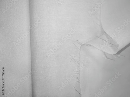 White texture of folded natural fabric with a crease and cut edge. Empty textured textile background