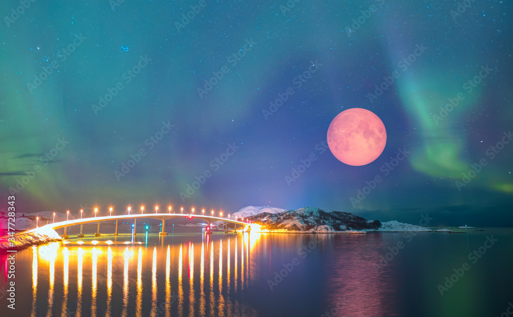 Sommaroy Bridge is a cantilever bridge connecting the islands of Kvaloya and Sommaroy with full moon and Aurora Borealis - Hillesoy Tromso Norway 