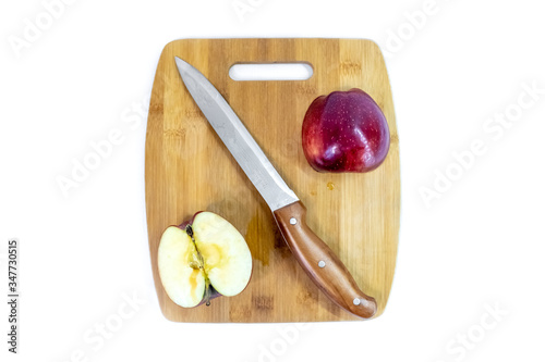 Sliced green apple with a kitchen knife is lying on a wooden board. Organic fruit. Healthy lifestyle. Sweet fruit. Natural vegetarian healthy food. White background.