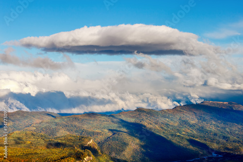 A cumulus cloud above fall forest in a mountains
