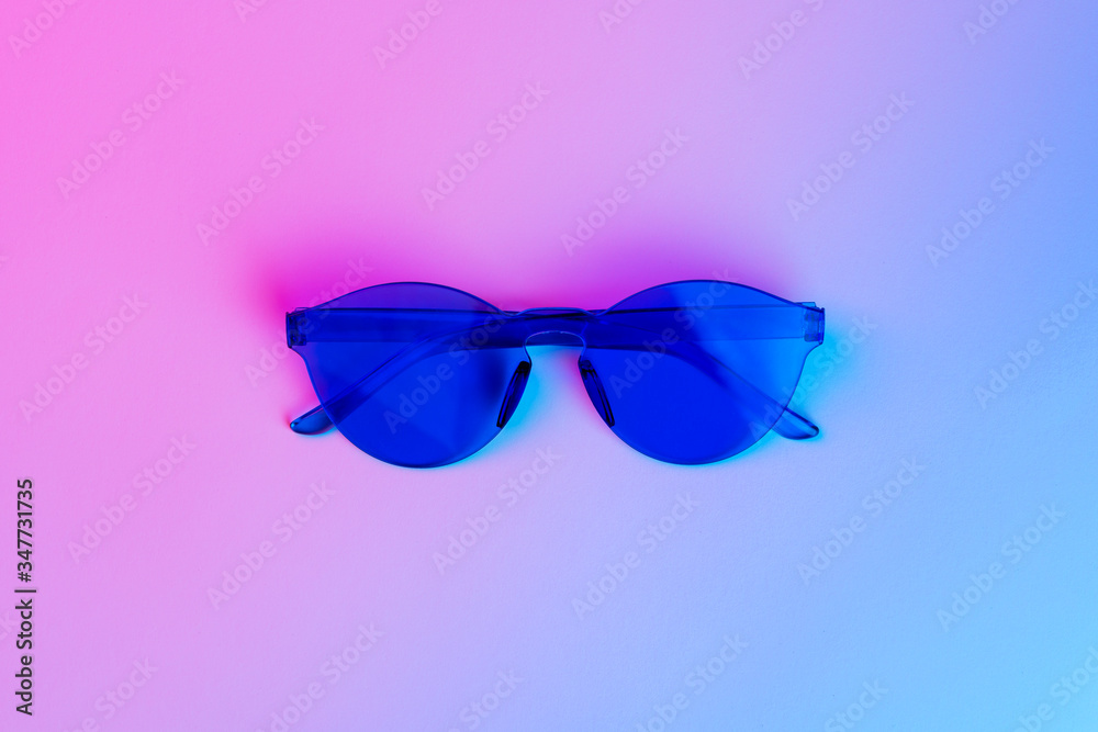 Fototapeta premium Blue plastic glasses for night party, purple neon light, minimalism