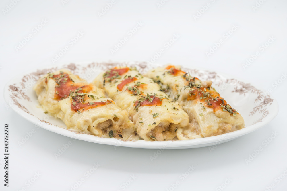 Canelones (cannelloni) with meat filled pasta and cheese and tomato on a plate