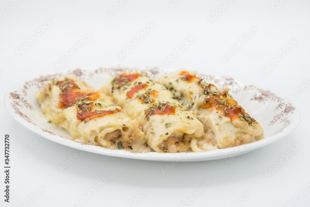 Canelones (cannelloni) with meat filled pasta and cheese and tomato on a plate Canelones (cannelloni) with meat filled pasta and cheese and tomato on a plate