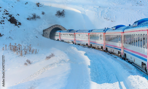 Red diesel train (East express) in motion at the snow covered railway platform - The train connecting Ankara to Kars - Passenger train going through tunnel 