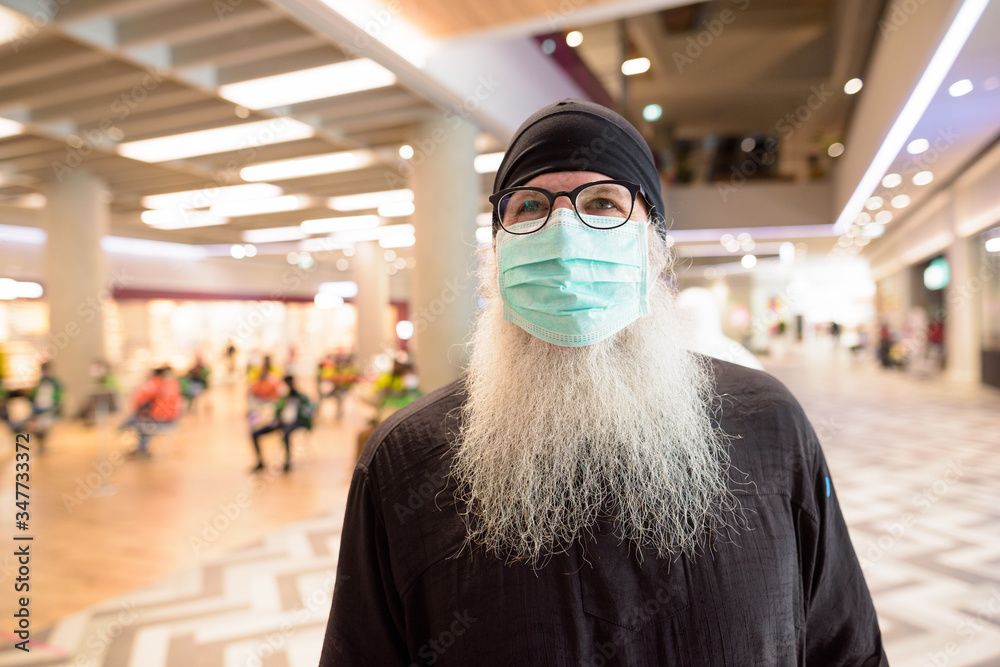 Mature bearded hipster man with mask for protection from corona virus outbreak shopping with distance at the mall Mature bearded hipster man with mask for protection from corona virus outbreak shopping with distance at the mall