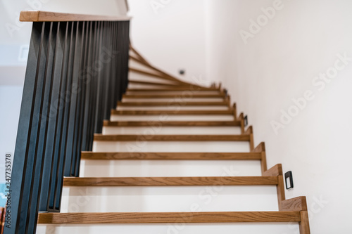 stylish wooden stairs in the apartment with handmade black metal railings