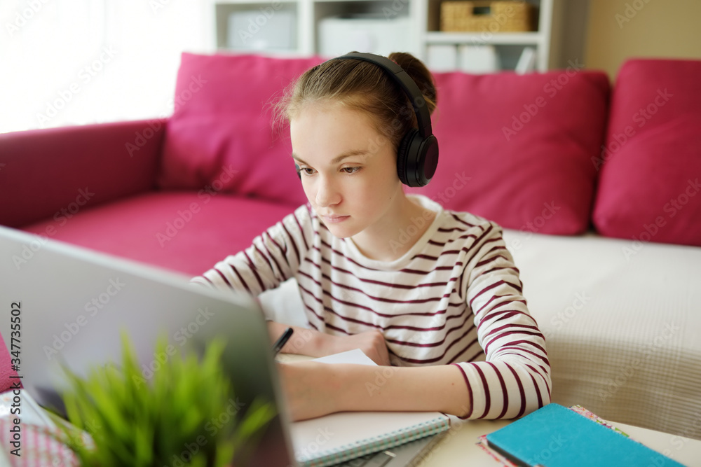 Preteen schoolgirl doing her homework with laptop computer at home. Child using gadgets to study. Online education and distance learning for kids. Homeschooling during quarantine. Preteen schoolgirl doing her homework with laptop computer at home. Child using gadgets to study. Online education and distance learning for kids. Homeschooling during quarantine.