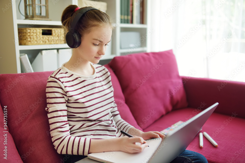 Preteen schoolgirl doing her homework with laptop computer at home. Child using gadgets to study. Online education and distance learning for kids. Homeschooling during quarantine. Preteen schoolgirl doing her homework with laptop computer at home. Child using gadgets to study. Online education and distance learning for kids. Homeschooling during quarantine.