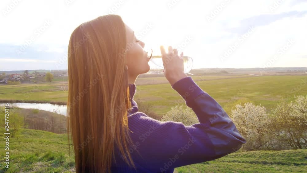 The beautiful woman drinking water from the bottle outdoor. slow motion The beautiful woman drinking water from the bottle outdoor. slow motion
