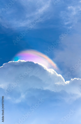 rainbow light on clouds with overcast blue sky