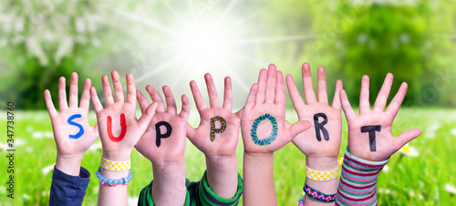 Children Hands Building Colorful English Word Support. Sunny Green Grass Meadow As Background