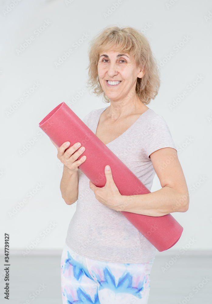 Sporty old woman holds a exercise mat Sporty old woman holds a exercise mat