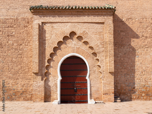 Wooden door of the Kutubiyya Mosque, Marrakesh, Morocco. Moroccan closed archway gate in stone terracotta wall with islamic ornaments