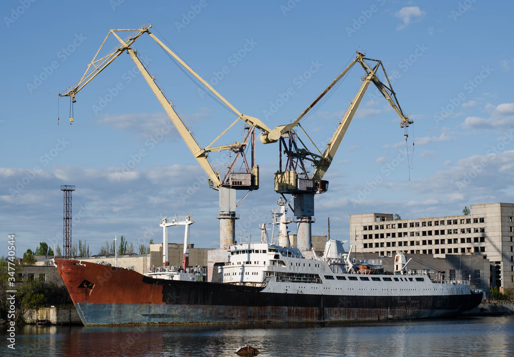 The ship is in port. Ship at the pier. Merchant ship. Rusty metal. Cargo crane.