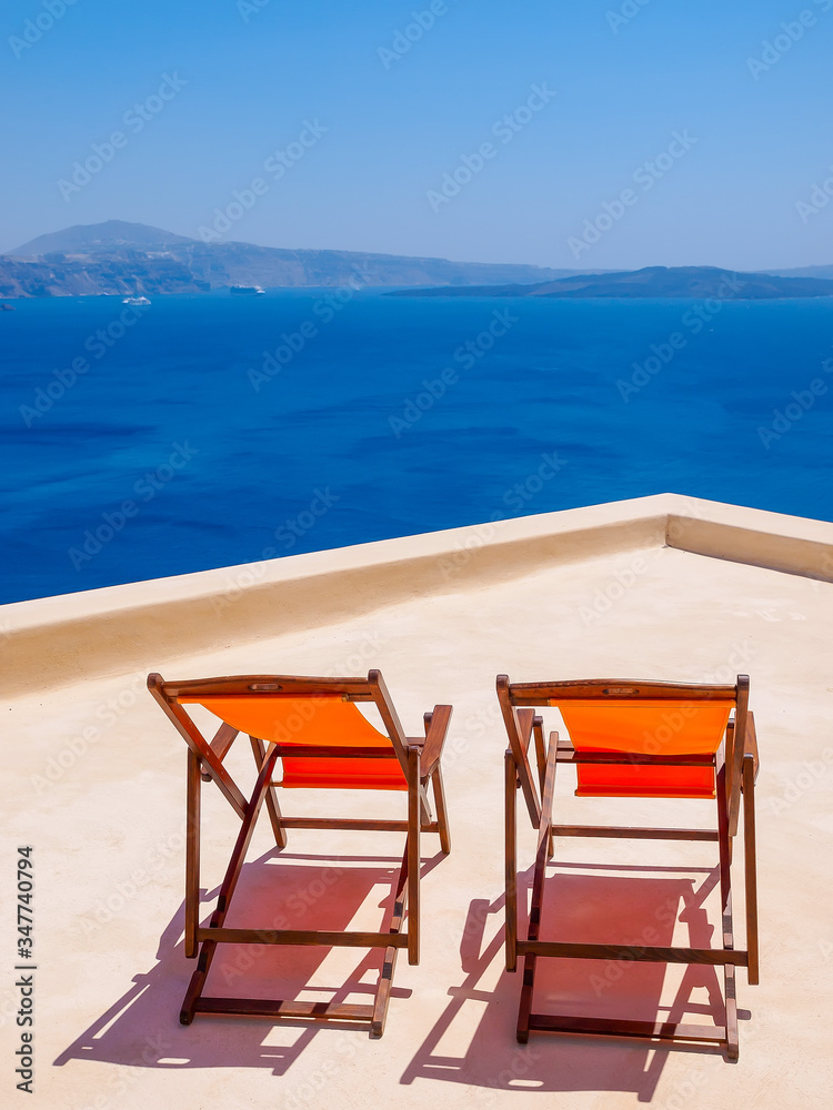 Two chairs on terrace and amazing Santorini volcano view. Santorini, Cyclades, Greece. Two chairs on terrace and amazing Santorini volcano view. Santorini, Cyclades, Greece.
