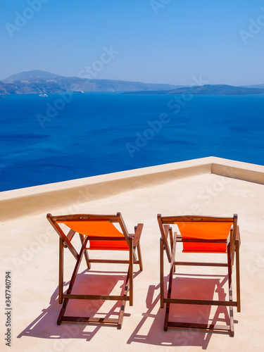 Two chairs on terrace and amazing Santorini volcano view. Santorini, Cyclades, Greece.