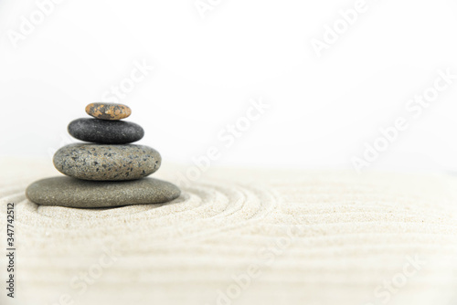 Zen garden. Pyramids of white and gray zen stones on the white sand with abstract wave drawings. Concept of harmony  balance and meditation  spa  massage  relax.