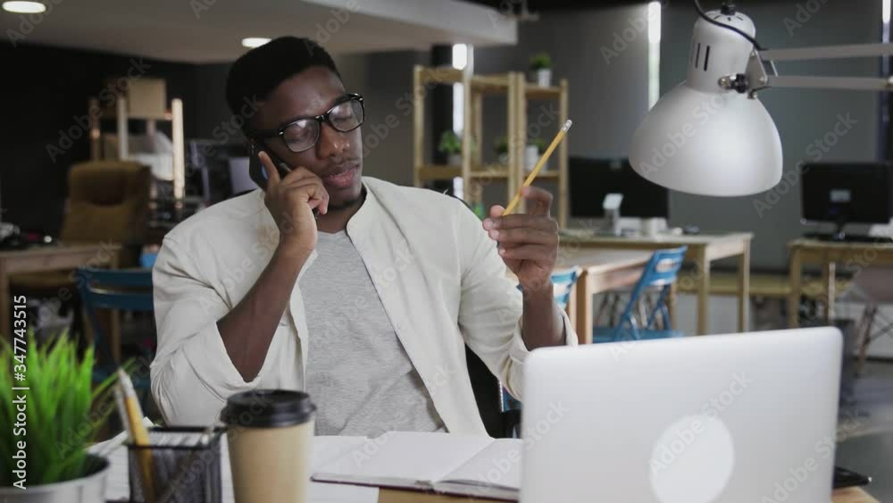 African man is talking on mobile phone and in modern office