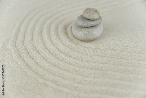 Zen garden. Pyramids of white and gray zen stones on the white sand with abstract wave drawings. Concept of harmony  balance and meditation  spa  massage  relax.