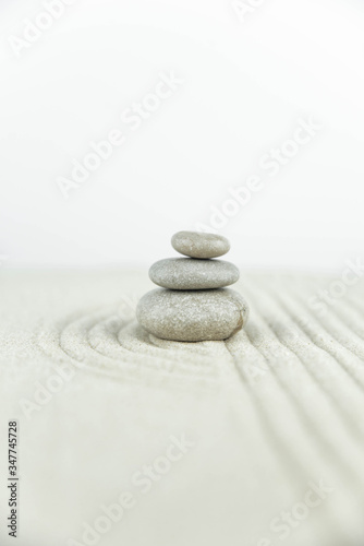 Zen garden. Pyramids of white and gray zen stones on the white sand with abstract wave drawings. Concept of harmony  balance and meditation  spa  massage  relax.