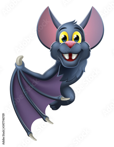 A cute Halloween vampire bat animal cartoon character peeking around from behind a sign and pointing at it with their wing