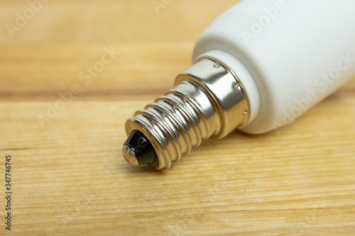 E14 light bulb close up on screw fitting. Wooden background.