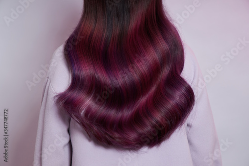 Portrait of a woman with bright colored flying hair, all shades of purple. Shiny Healthy colored Hair coloring, beautiful lips and makeup. Sexy girl with long hair styling
